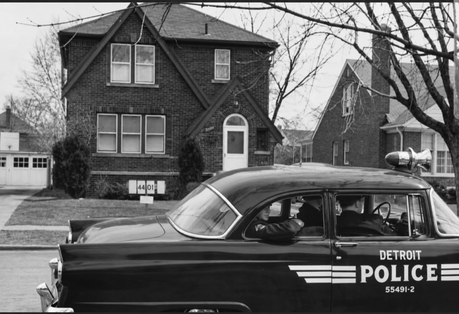 Historic Detroit police patrol car traveling through a residential neighborhood